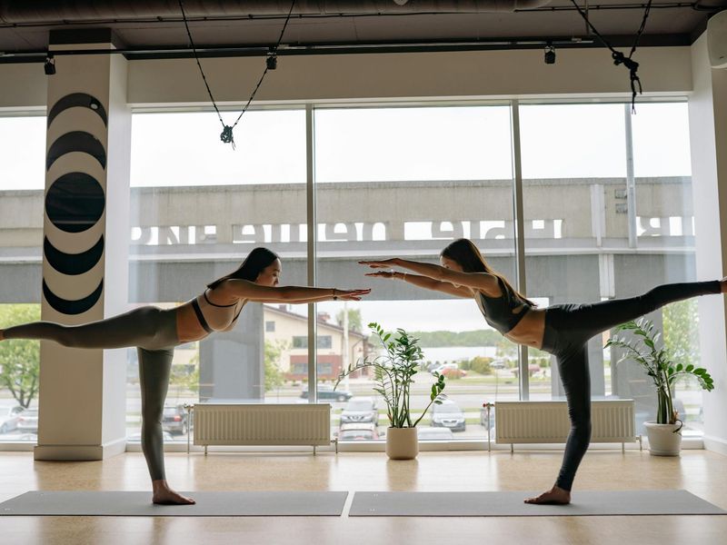 Person transitioning smoothly between two yoga poses in a minimalist studio.